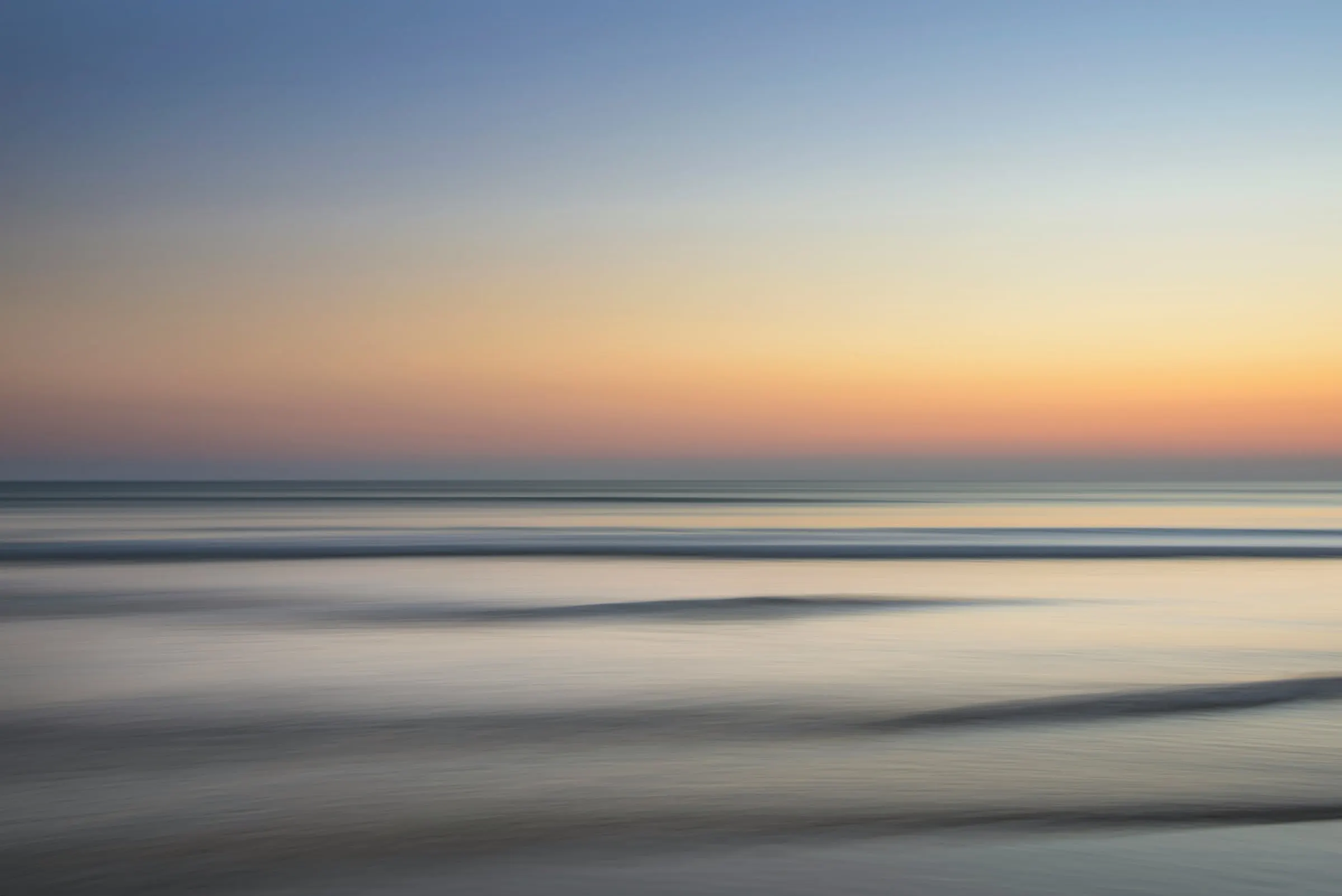 A calm sea at dusk under a softly glowing horizon